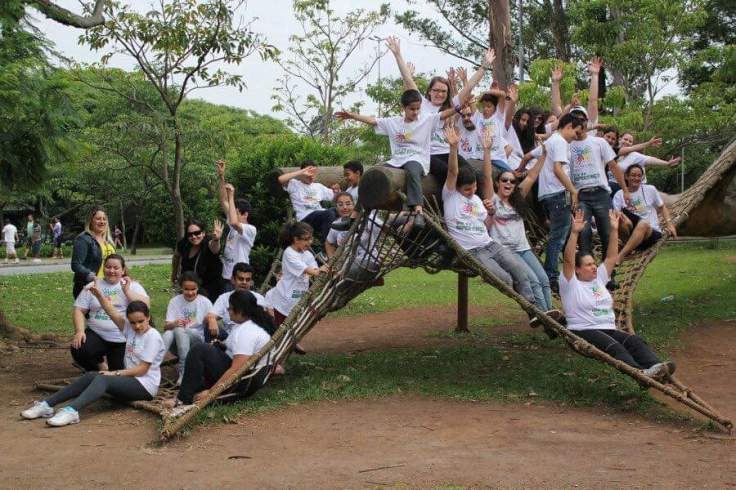 Gabrielli entre os alunos do projeto Ver Com As Mãos em cima de uma escultura no parque Ibirapuera